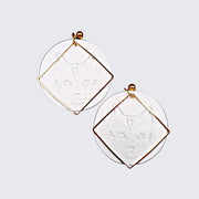 Pendientes circulares con silueta de gato y acabados con un cuadrado de metal dorado.